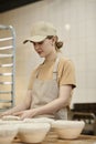 Young woman making fresh bread in bakery and kneading dough Royalty Free Stock Photo