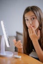 Vertical portrait Young woman trying to apply contact lenses in front of mirror. Young girl trying on new contact lenses. Close up Royalty Free Stock Photo