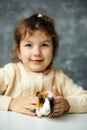 Vertical positive, playful girl holding, playing small multicolored guinea pig sit on white table. Present for holiday Royalty Free Stock Photo