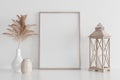 Vertical poster art mockup with wooden frame, dry plant in vase and wooden candlestick on empty white background