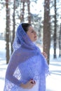 Vertical profile portrait of a cute girl in a lovely pale lavender knitted shawl against a winter forest Royalty Free Stock Photo