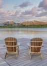 Vertical Puffy clouds at sunset Four wooden lounge chairs facing the reflective Oquirrh Lake at