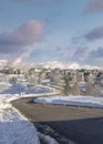 Vertical Puffy clouds at sunset Plowed road in the snow covered residential community of Draper