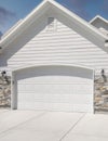 Vertical Puffy clouds at sunset Three car garage exterior with two white garage doors with arche Royalty Free Stock Photo