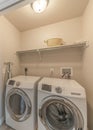 Vertical Reached in laundry with white bi-fold doors and laundry units below the shelf