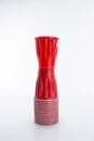 Vertical of a red disposable plastic cup put on a horizontal stack of cups against white background