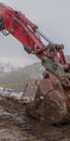 Vertical Red excavator and barricade on a muddy mountain road viewed in winter Royalty Free Stock Photo