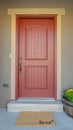 Vertical The red front door of a house with concrete exterior wall and shutters on window Royalty Free Stock Photo