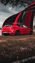 Vertical red SEAT Leon car on the lakeshore during an event