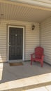 Vertical Red wooden armchair by the brown door at the small front porch of a home Royalty Free Stock Photo