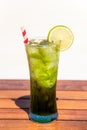 Vertical refreshing mojito mocktail with straw on wooden table at the beach