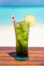 Vertical refreshing mojito mocktail with straw on wooden table ocean background at the beach