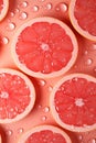 vertical ripe juice sliced red grapefruit in water drops on pink background top view