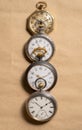 Vertical row of four antique gold and silver pocket watches on beige background. Retro mechanical watch with white dials Royalty Free Stock Photo