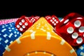 Vertical rows of colored casino chips and many red dice on isolated black background. Set of yellow, blue and pink Royalty Free Stock Photo