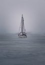 Vertical of a sailboat sailing on a cloudy day in open water Royalty Free Stock Photo