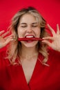 Vertical satisfied and glad, expressive blonde woman eat red chili pepper with open mouth with close eyes. Advertisement Royalty Free Stock Photo