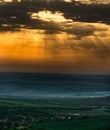 Vertical scenic shot of the setting sun shining above the sea, a coastal village nearby