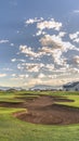 Vertical Scenic view at a golf course with focus on sand trap and fairway on a sunny day Royalty Free Stock Photo