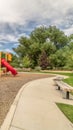 Vertical Scenic view at a park with colorful childrens playground and benches on pathway