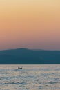 Vertical of seascape view at sunset with a boat swimming in water, a purple and misty sky background Royalty Free Stock Photo