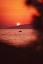 Vertical of seascape view at sunset with a boat swimming in water, a purple and misty sky background Royalty Free Stock Photo