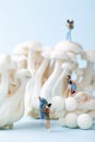 Vertical selective focus closeup of a toy people hiking on the mushrooms on a blue background