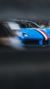 Vertical selective focus shot of blue Ferrari car seen through blur metal fence