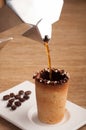 Vertical selective focus shot of coffee pouring in a cup made of biscuit Royalty Free Stock Photo