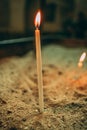 Vertical selective focus shot of lighting candle in church