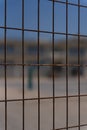 Vertical selective focus view of a metal fence made of wires with a basketball court behind