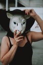Vertical selective shot of a female with white sheep mask wearing black hat and top Royalty Free Stock Photo