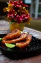 Vertical shallow focus closeup shot of grilled meat slices with lime in a black plate on a table Royalty Free Stock Photo