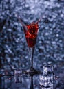 Vertical shallow focus closeup shot of ice cubes falling into a glass of red drink Royalty Free Stock Photo