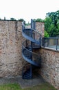 Vertical shoot of spiral stairs near a stone building with green trees in the background Royalty Free Stock Photo