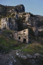 Vertical shot of an abandoned stone building right next to a big cliff