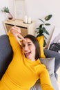 Vertical shot of young pretty woman taking selfie portrait lying on sofa at home