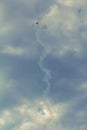 Vertical shot of an airplane with a white smoke tail against a dramatic cloudy sky