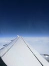 Vertical shot of an airplane wing over clouds with dark blue sky on the background Royalty Free Stock Photo