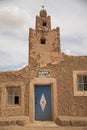 Vertical shot of an ancient building with a blue door under a clouded sky Royalty Free Stock Photo