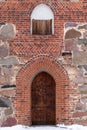 Vertical shot of an ancient wooden door on a background of a bricky wall