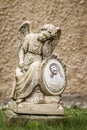 Vertical shot of an angel statue with an image of Christ and a blurred background Royalty Free Stock Photo