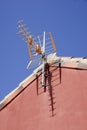 Vertical shot of an antenna attached to a red house on a clear blue background