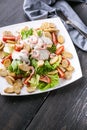 Vertical shot appetizing salad with shrimp, lettuce, cheese, avocado and crackers on a white plate. Delicious and healthy seafood Royalty Free Stock Photo