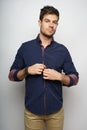 Vertical shot of an attractive male buttoning his shirt isolated on a white background