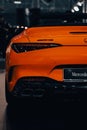 Vertical shot of the back side of an orange luxury Mercedes-Benz AMG SL with blur background