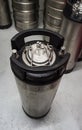 Vertical shot of a ball lock type keg with co2 input and beer output visible