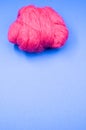 Vertical shot of a ball of pink yarn on a blue surface Royalty Free Stock Photo