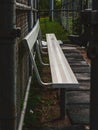 Vertical shot of a baseball bench for the team after the rain with metal fence in the background