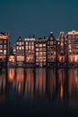 Vertical shot of beautiful Amsterdam waterfront buildings under the blue sky at night